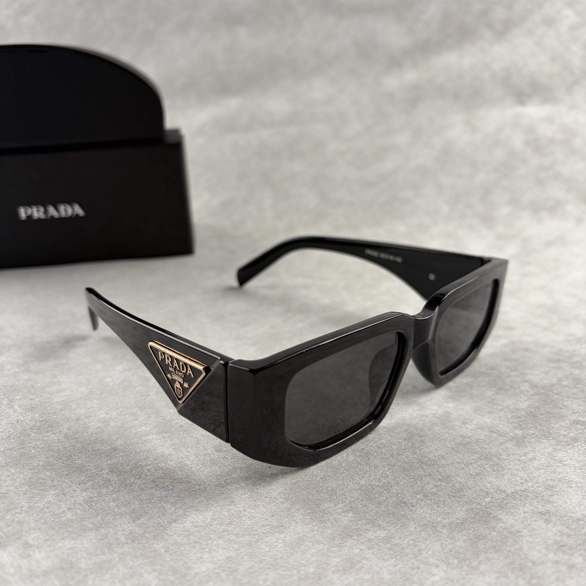 Modern black rectangular sunglasses with dark lenses and thick frame, isolated on a light background