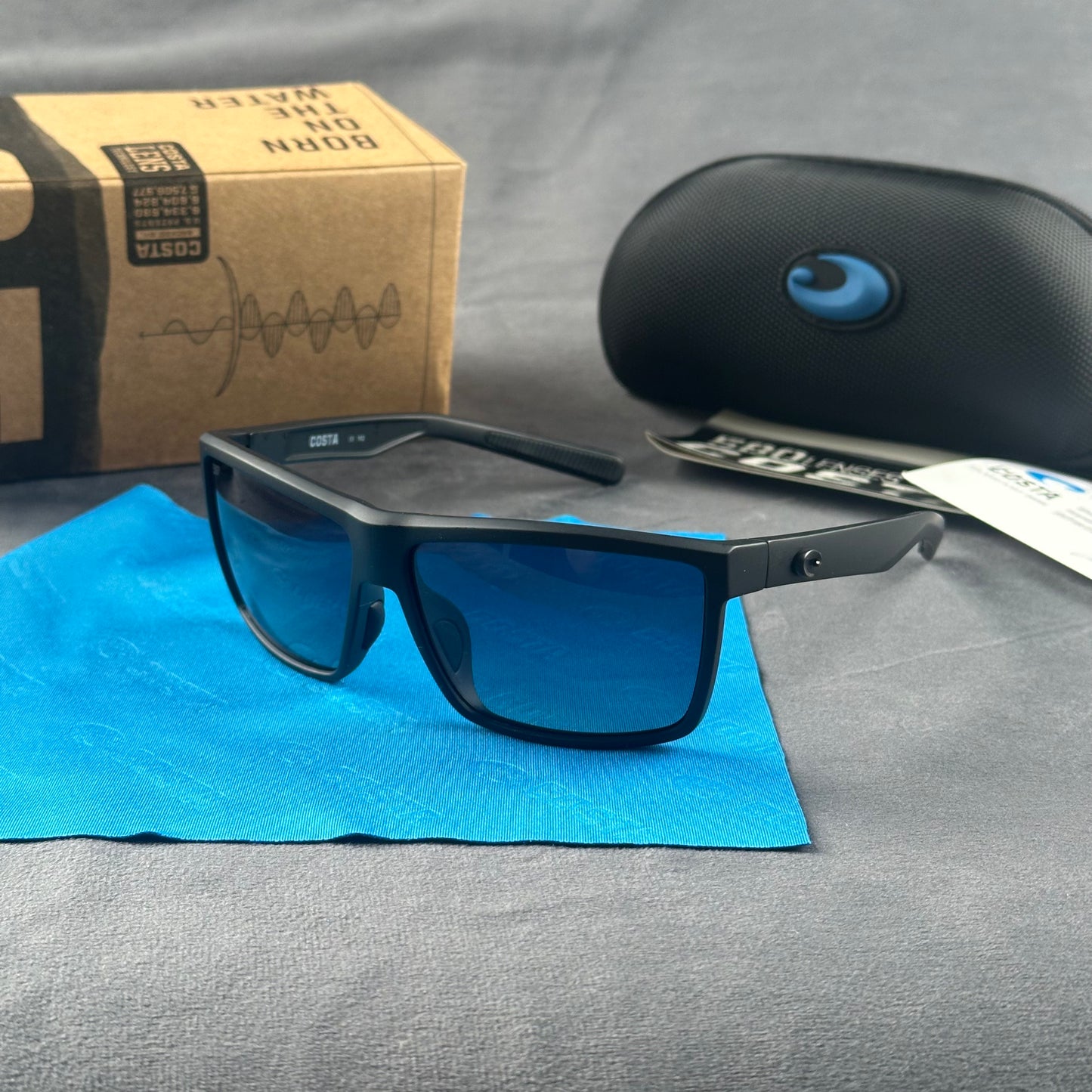 Matte black sport sunglasses with polarized blue-tinted lenses, hard case, and cleaning cloth.
