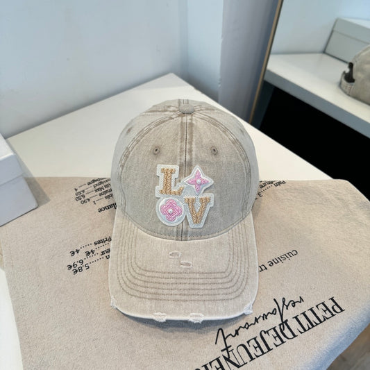 Distressed beige baseball cap with intricate floral letter embroidery and pearl details.