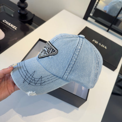 A light blue distressed denim baseball cap with a triangular embroidered patch on the front.