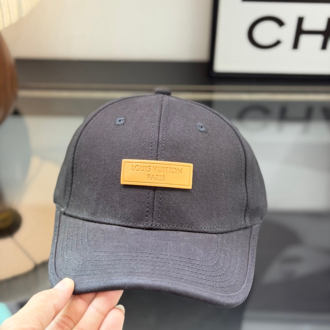A structured black cotton baseball cap with a rectangular tan faux-leather patch on the front.