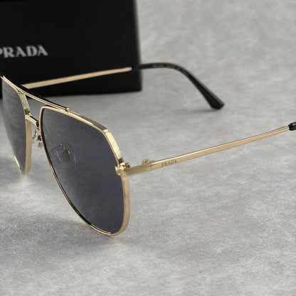 A pair of gold metal aviator sunglasses with dark lenses resting on a light grey textured background