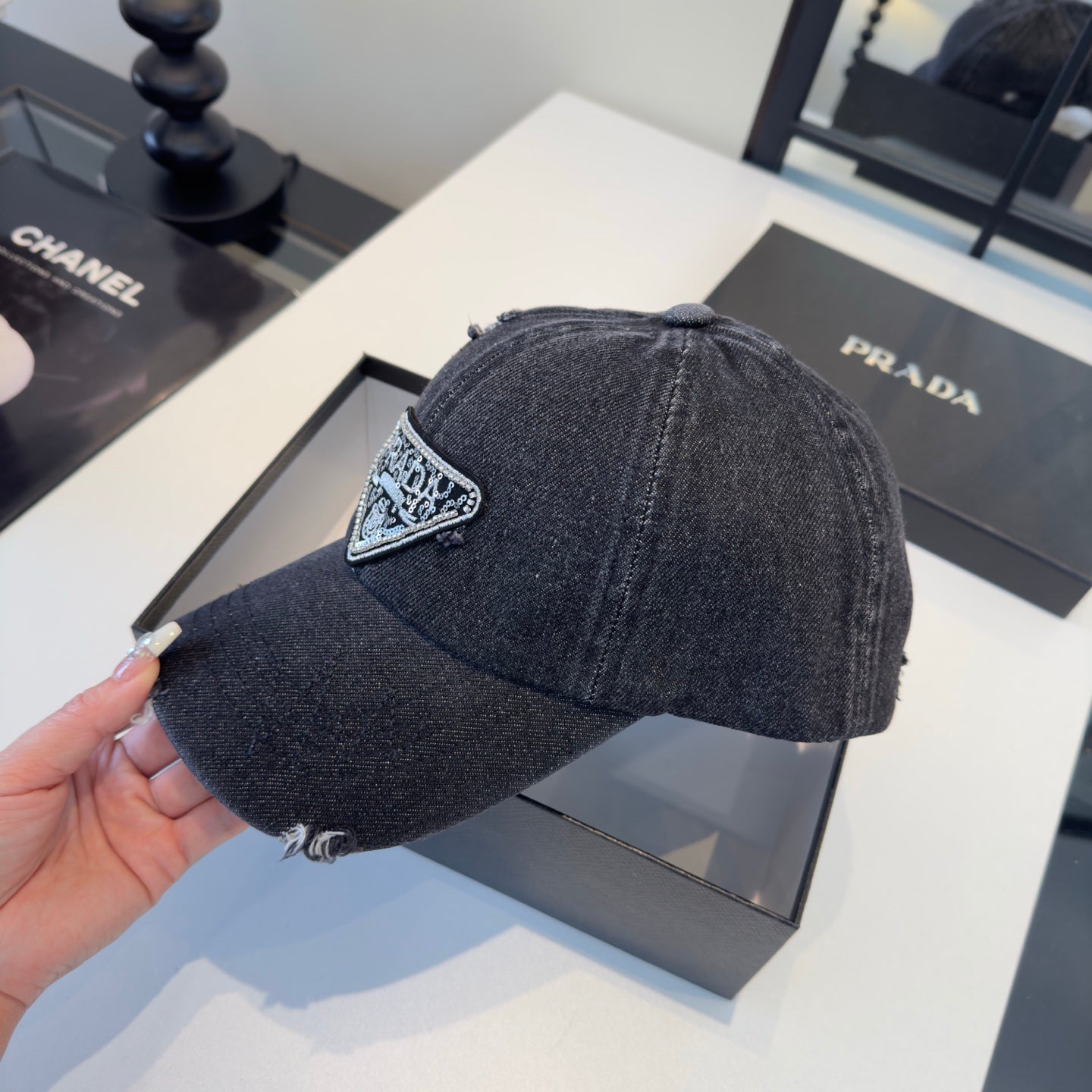A black distressed denim baseball cap with a sparkling triangular patch on the front center.