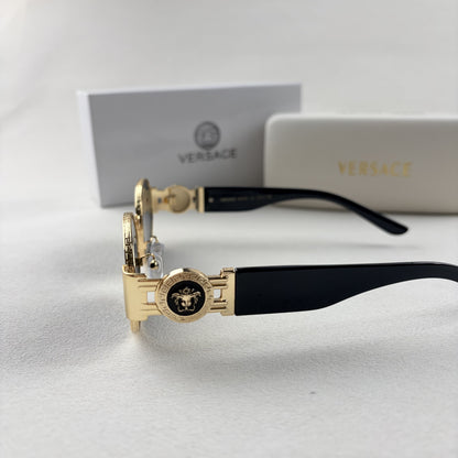 Oval gold metal frame sunglasses with black temples and dark tinted lenses, shown with a storage cas