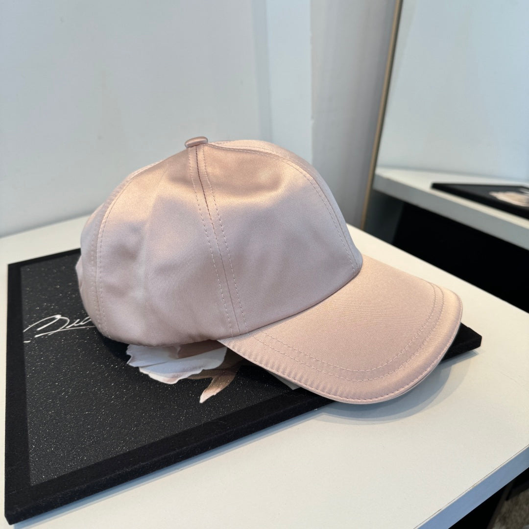 Dusty pink satin baseball cap with a curved brim, featuring a minimalist adjustable back strap.