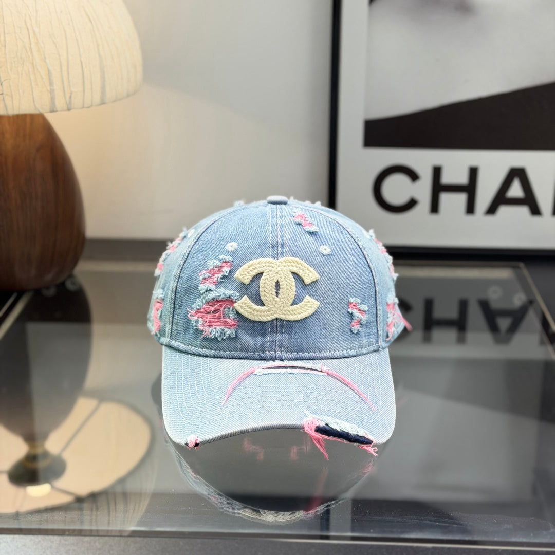 Distressed light wash denim baseball cap with frayed pink stitching and embroidery on the front.