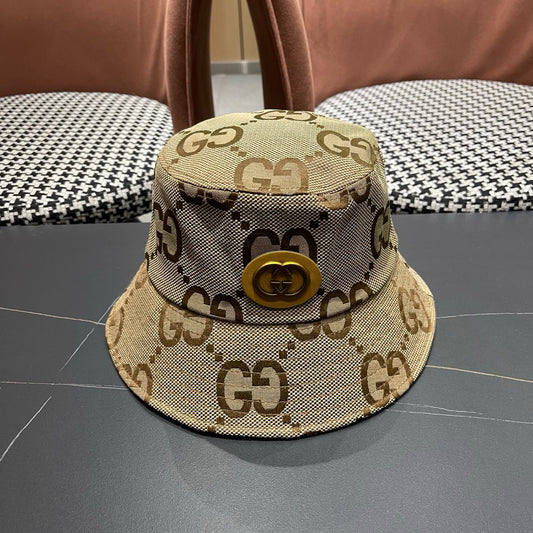 A beige canvas bucket hat with an all-over brown monogram pattern and a decorative gold-toned emblem