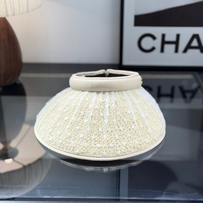 A beige straw sun visor with white polka dot mesh overlay and a gold metallic logo detail.