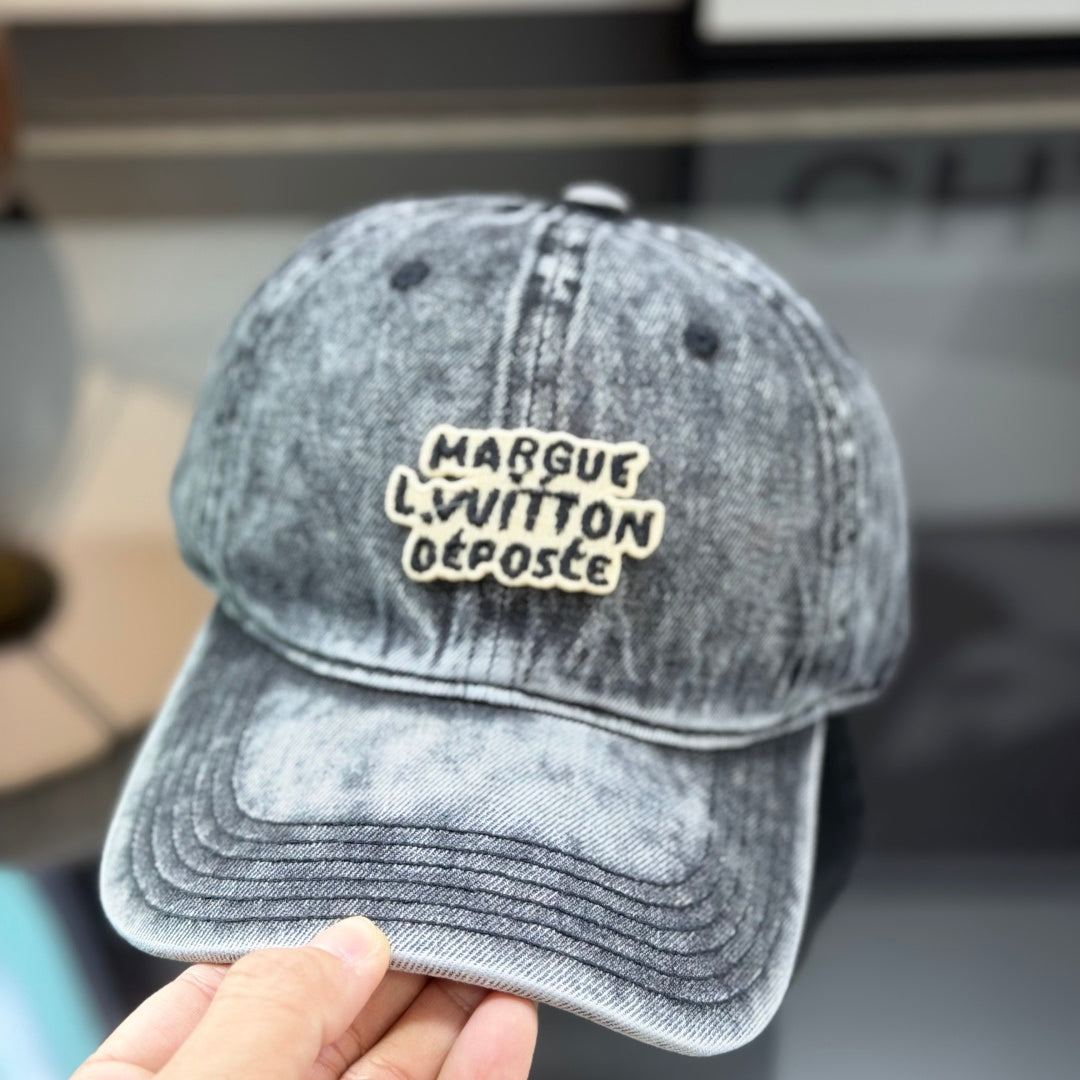 A grey distressed washed denim baseball cap with an embroidered patch on the front panel.