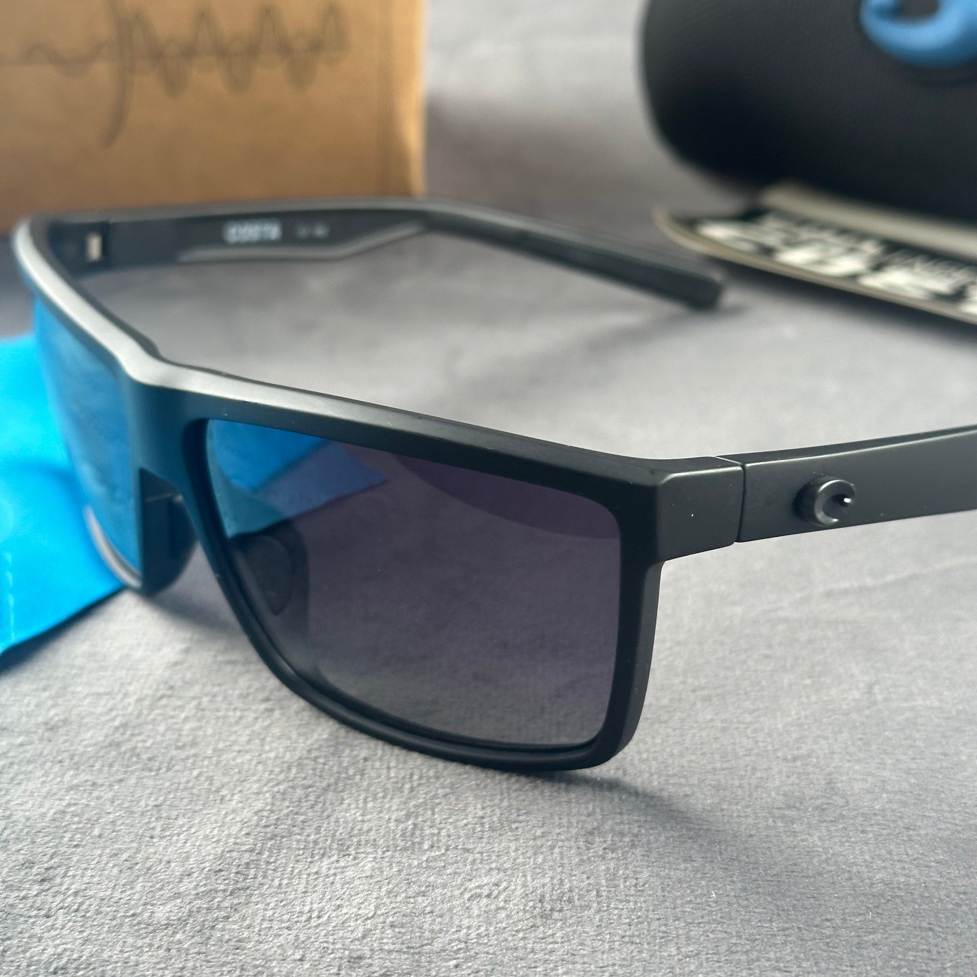 Matte black sport sunglasses with polarized blue-tinted lenses, hard case, and cleaning cloth.