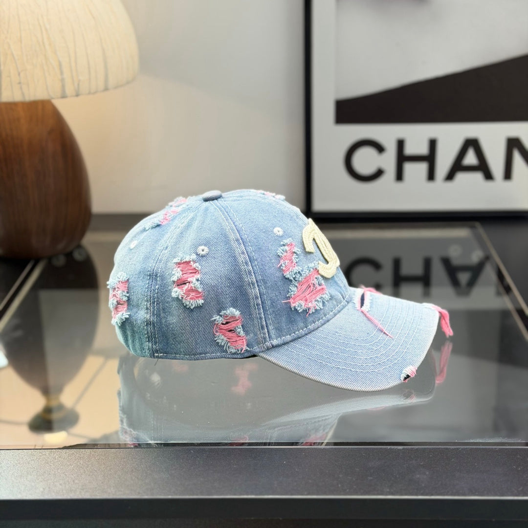 Distressed light wash denim baseball cap with frayed pink stitching and embroidery on the front.