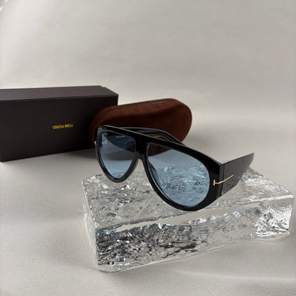 Black acetate oversized aviator sunglasses with blue tinted lenses resting on a clear ice-like block