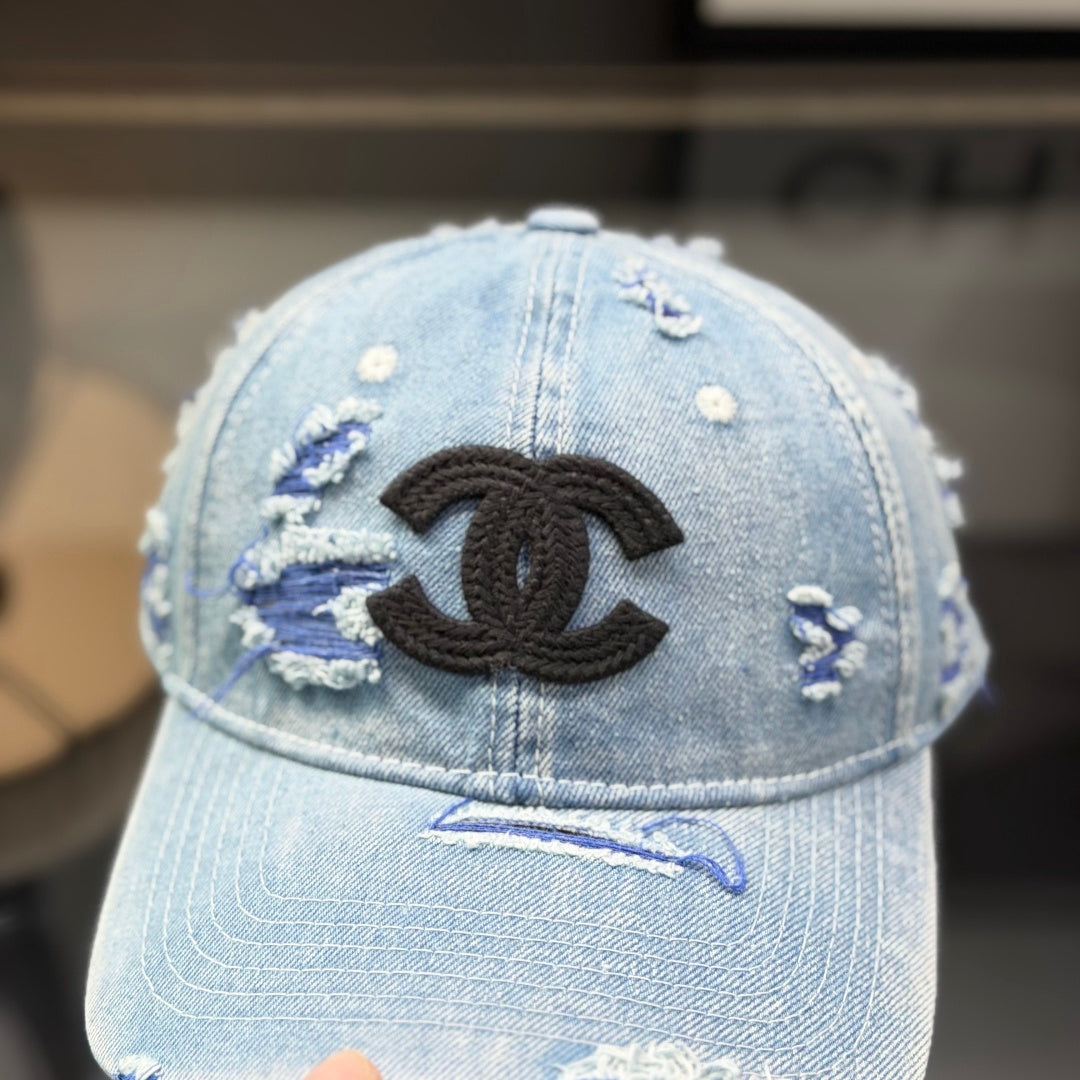 Distressed light wash denim baseball cap with frayed edges and embroidered front emblem.