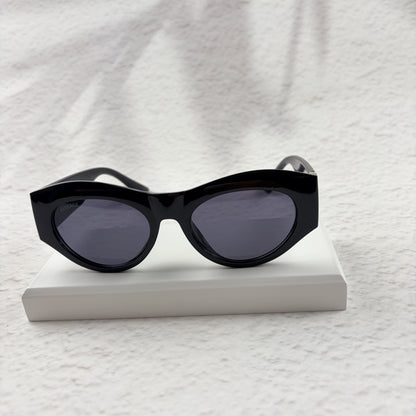 Black cat-eye sunglasses featuring gold-toned baroque temple embellishments on a white textured base
