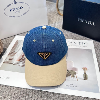 A two-tone baseball cap with a blue denim crown, beige brim, and a triangular metal logo badge.