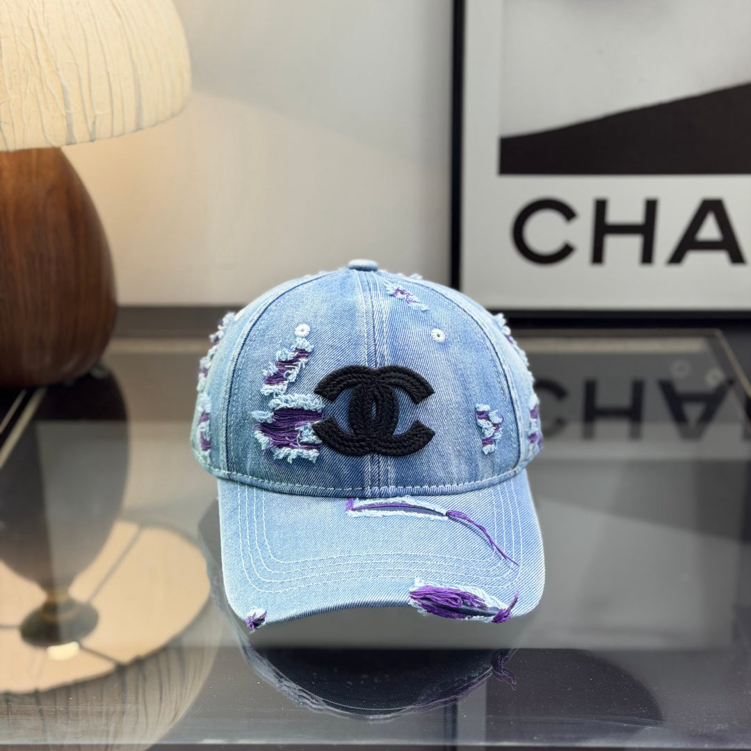Distressed blue denim baseball cap with frayed detailing and a central stitched logo emblem.