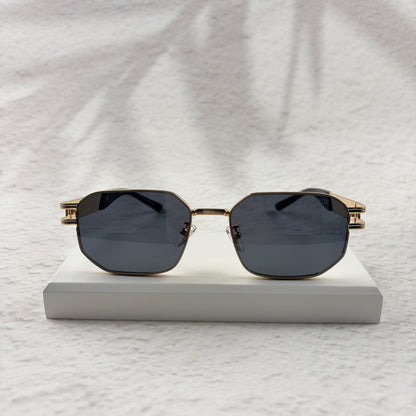 Gold tone metal frame geometric sunglasses with dark lenses on a white display block.