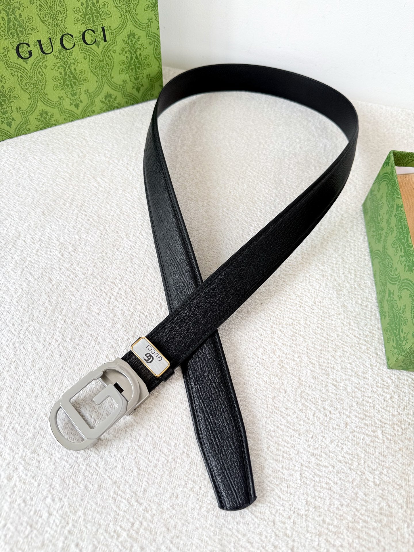 Premium black leather belt with a modern silver automatic steel buckle and detailed grain texture.