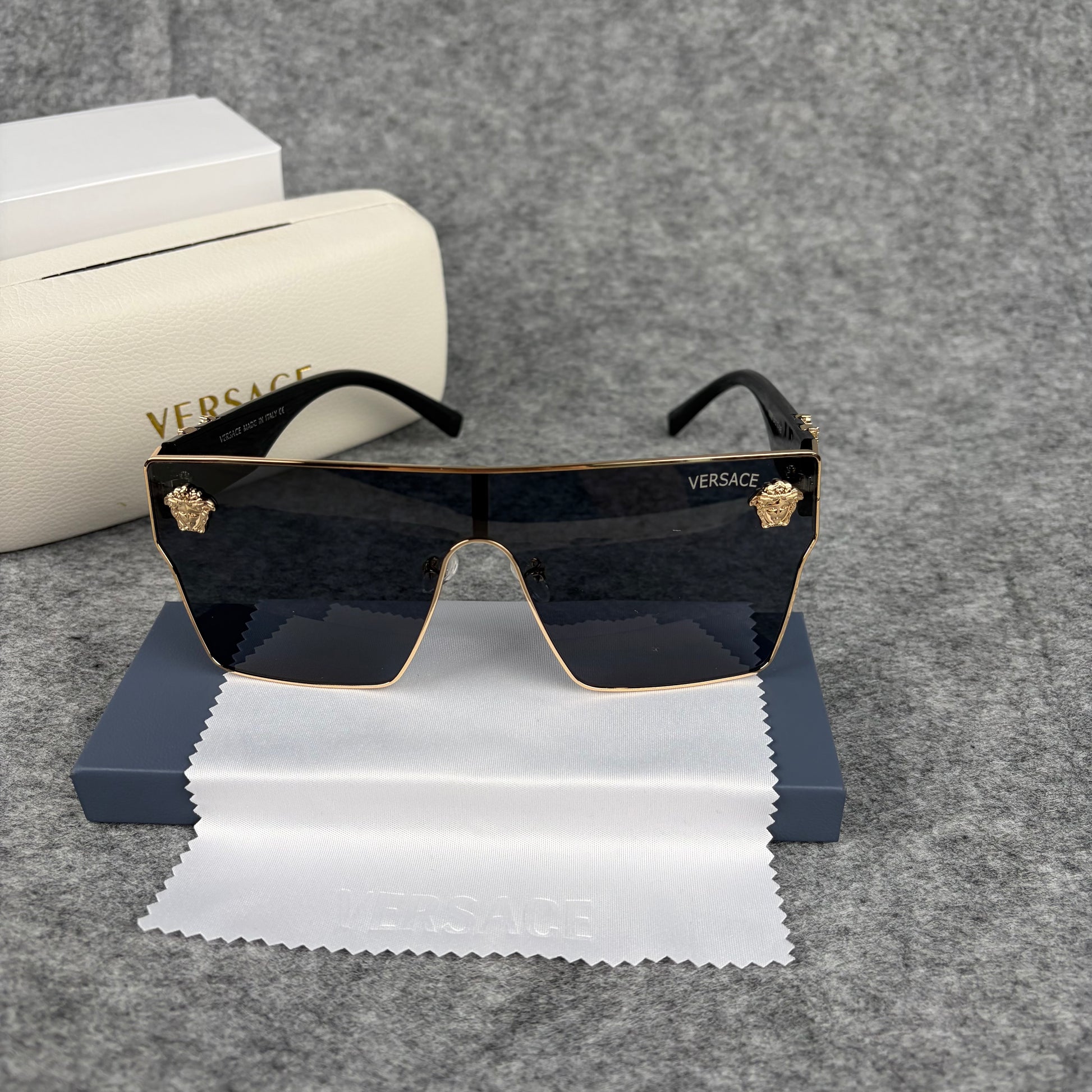 Oversized flat-top shield sunglasses with black lenses and decorative gold-tone metal side accents.