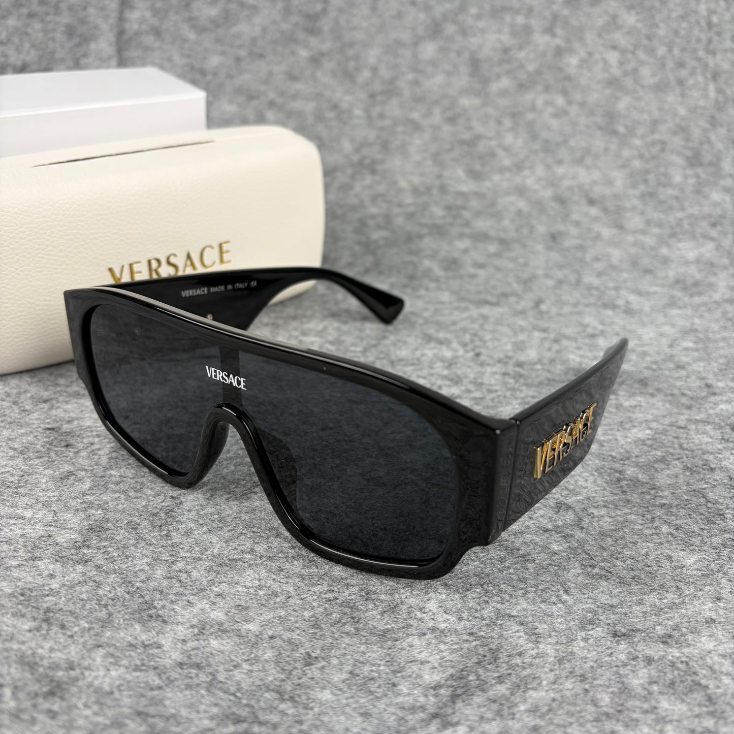 Oversized black shield sunglasses with a clean, modern aesthetic and protective hard storage case.
