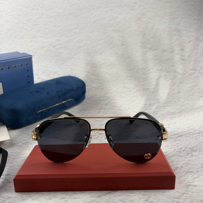 Pilot sunglasses with gold frame accents and dark lenses on a red display case.