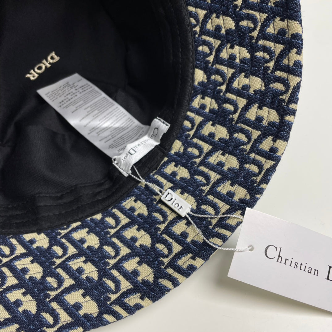 Close-up of a premium navy and beige monogram patterned bucket hat with central gold embroidery.