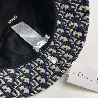 Close-up of a premium navy and beige monogram patterned bucket hat with central gold embroidery.