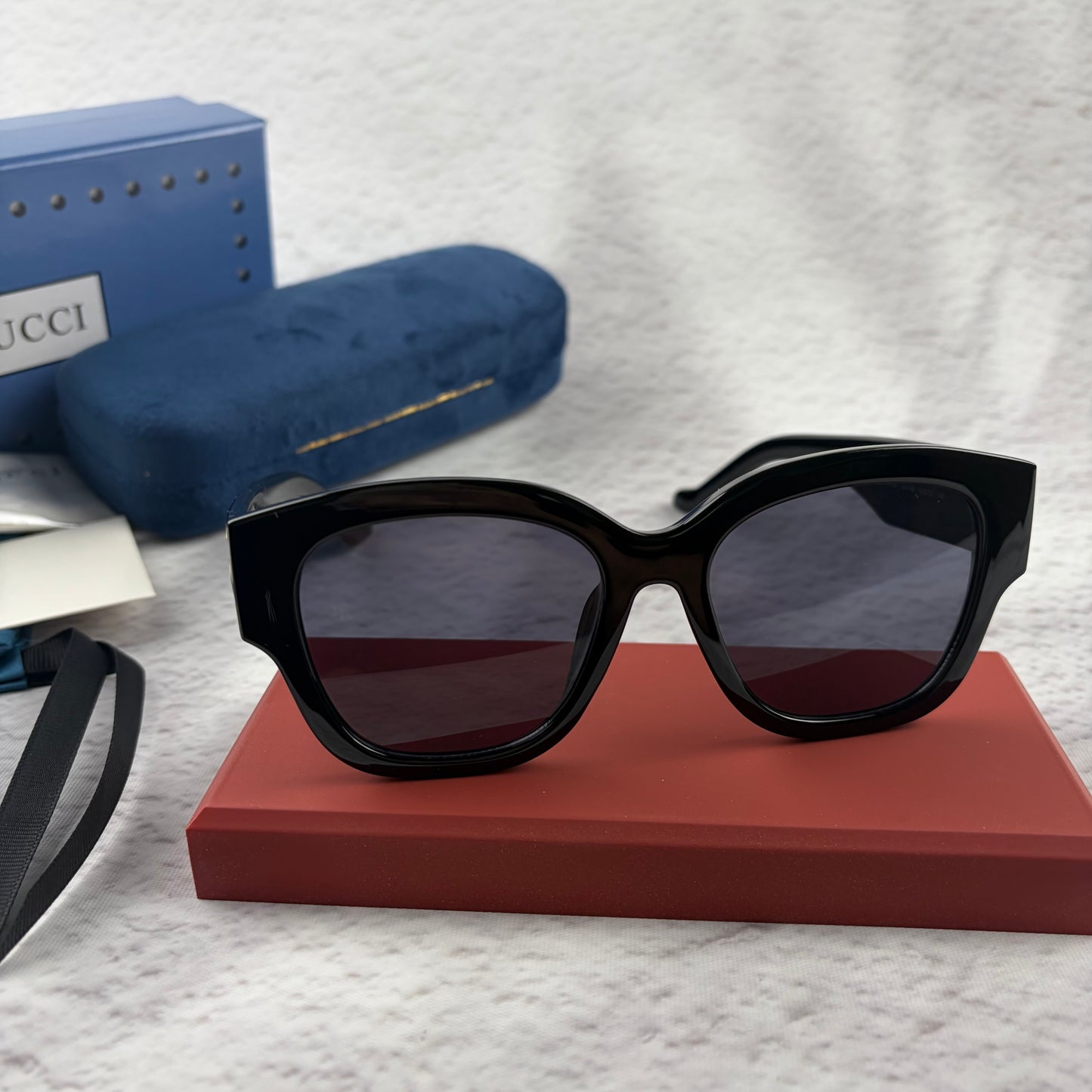 Oversized black frame sunglasses with dark gradient lenses and gold-tone logo detailing on temples.