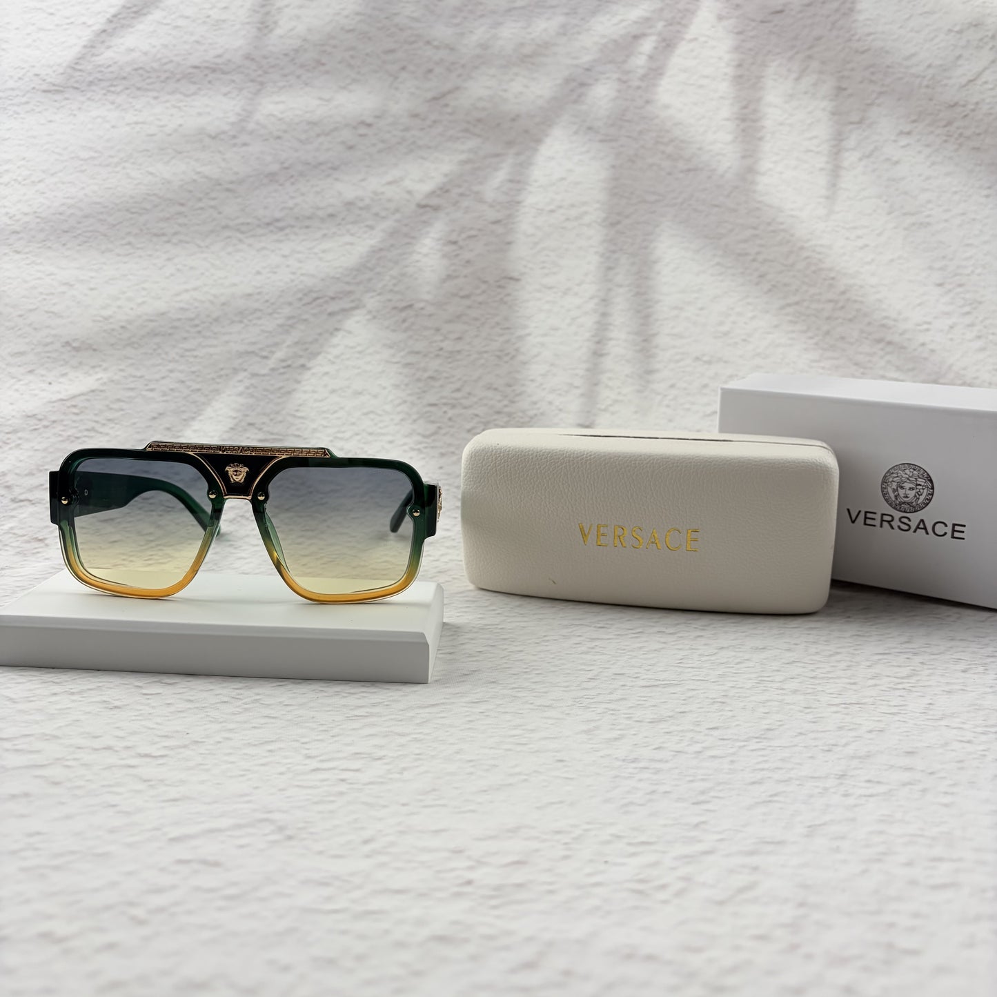 Oversized geometric sunglasses with green-to-yellow gradient lenses and gold metallic frame details.