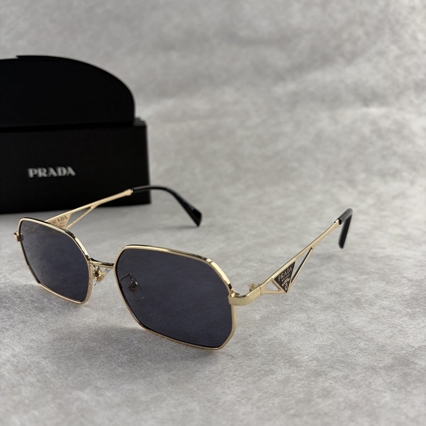 Geometric metal-frame sunglasses in gold tone with dark smoke lenses and signature triangular temple