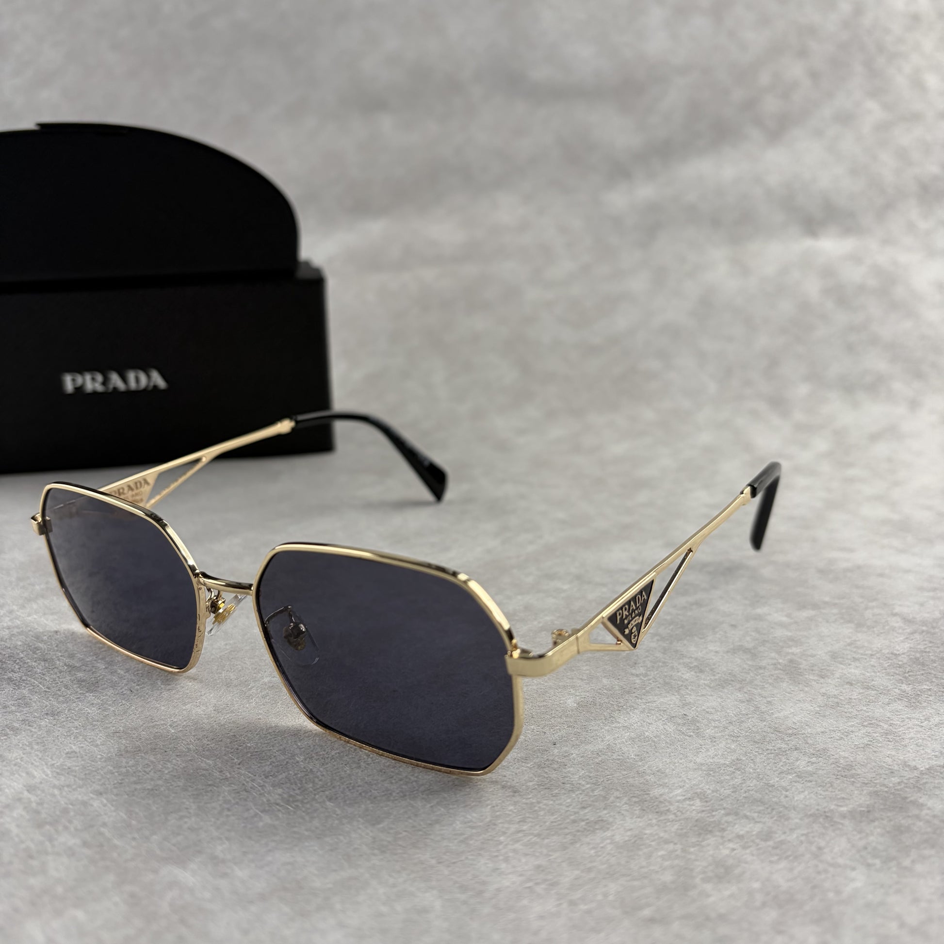 Geometric metal-frame sunglasses in gold tone with dark smoke lenses and signature triangular temple