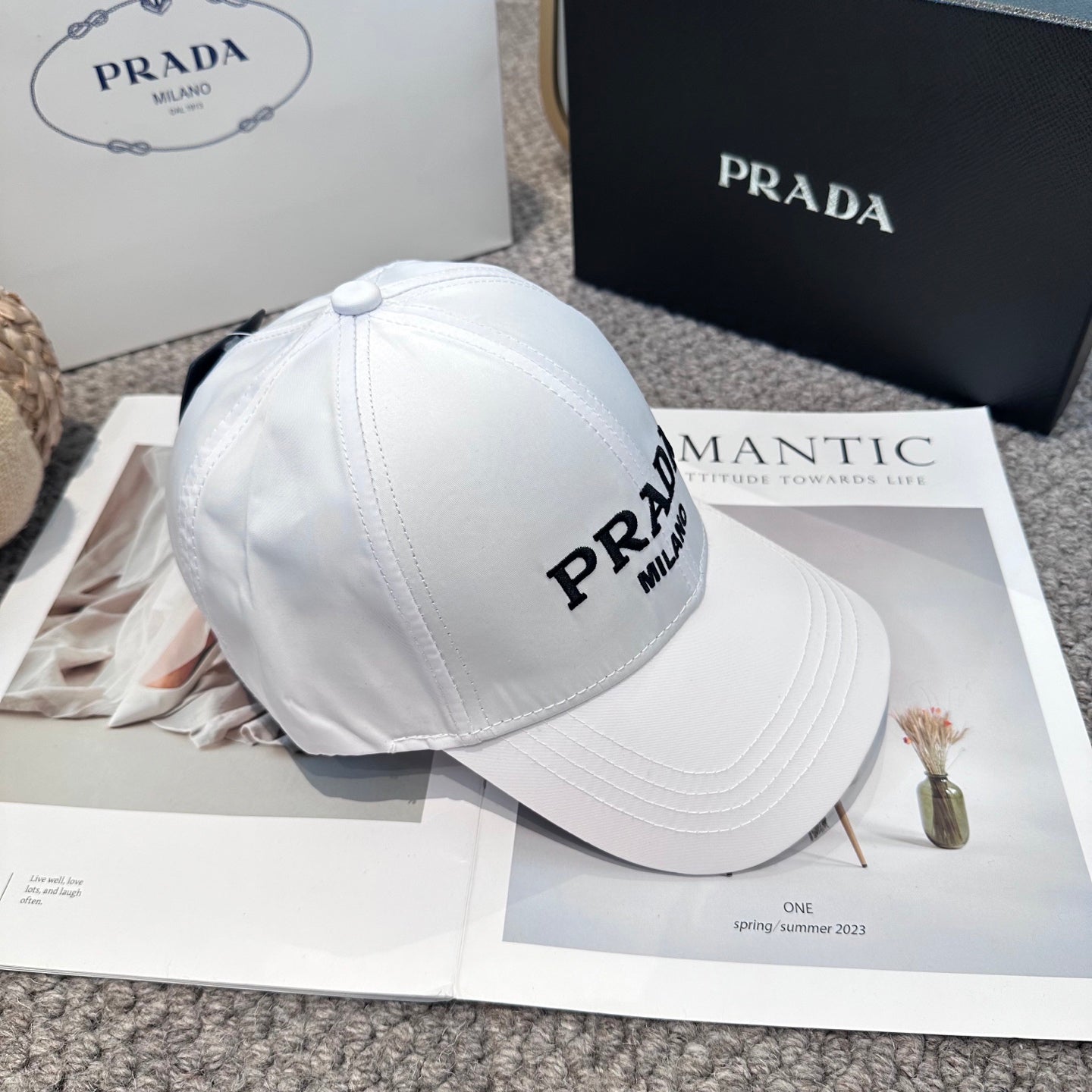 A clean white baseball cap featuring black embroidered lettering, structured crown, and curved visor