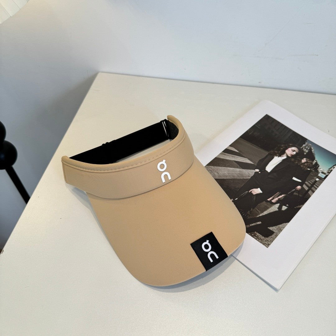 A beige lightweight sport visor with adjustable elastic band, featuring a minimalist logo design.