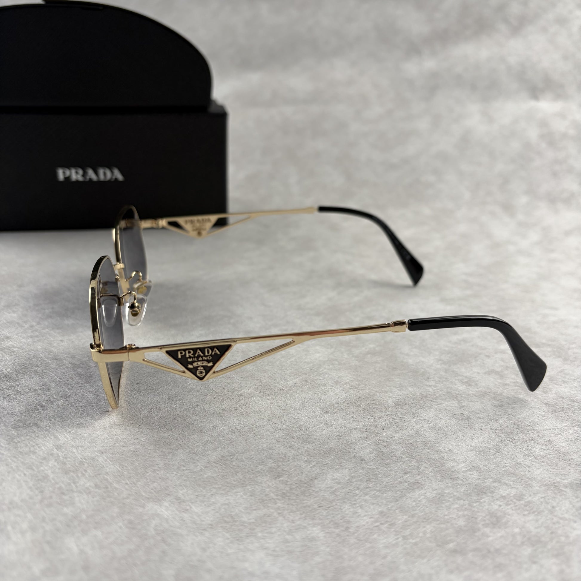 Geometric metal-frame sunglasses in gold tone with dark smoke lenses and signature triangular temple