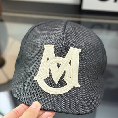 Close-up of a premium dark grey textured ivy cap with a white embroidered logo, high-quality fabric.