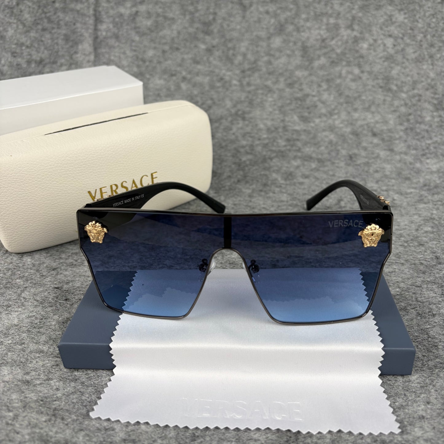 Oversized shield sunglasses with gradient blue lenses and gold metallic accents on the side arms.
