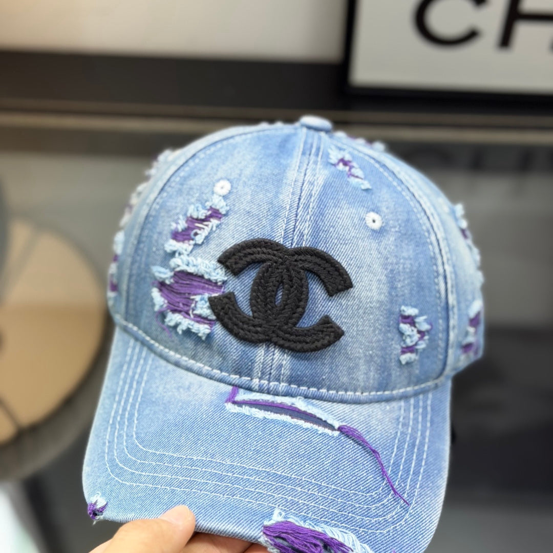 Distressed blue denim baseball cap with frayed detailing and a central stitched logo emblem.