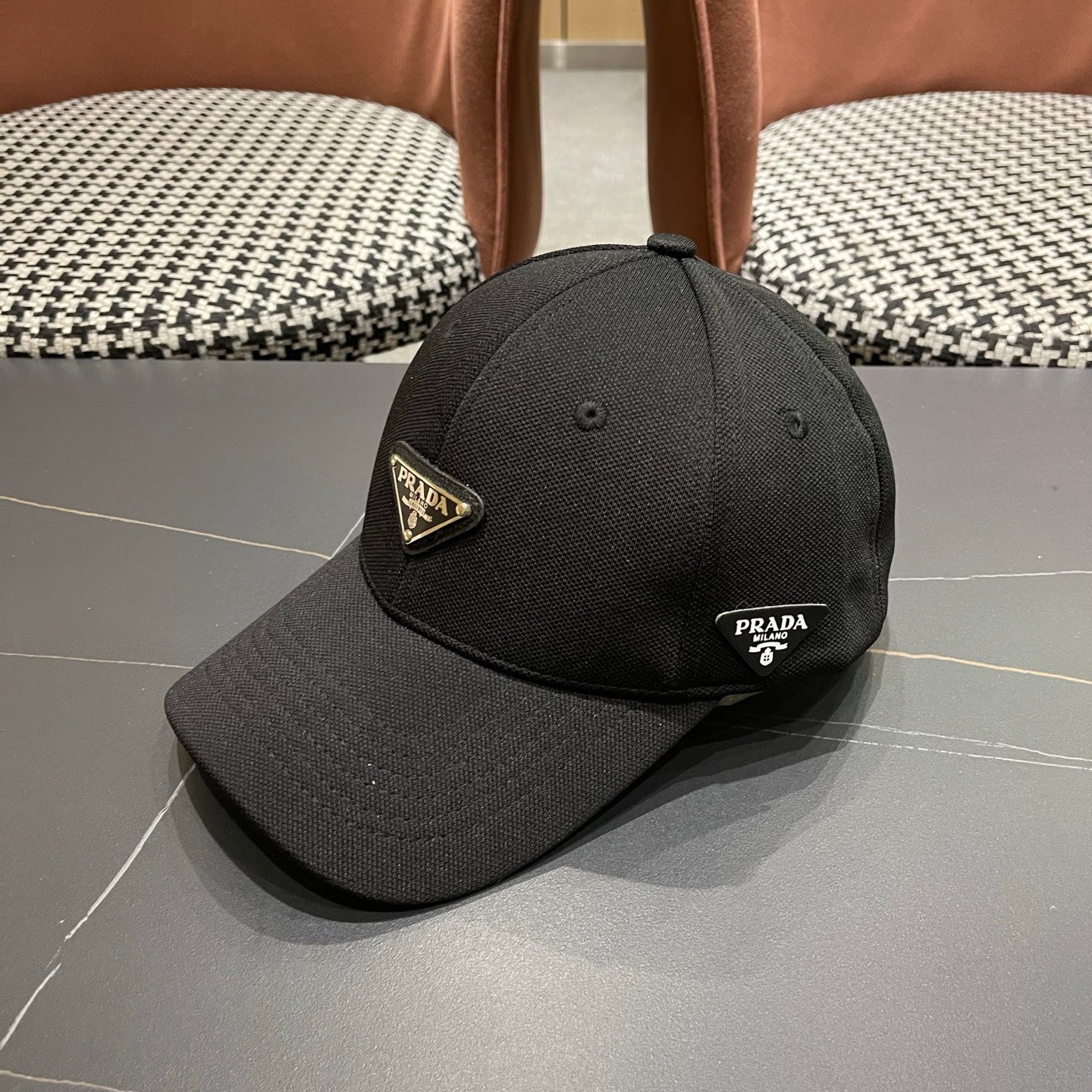 A black premium structured baseball cap with a centered metal triangular emblem on the front.