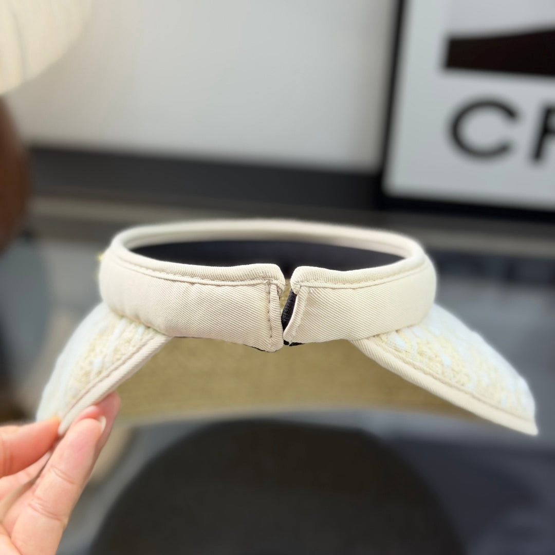 A beige straw sun visor with white polka dot mesh overlay and a gold metallic logo detail.
