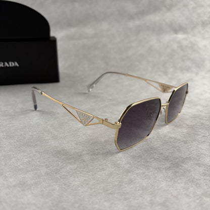 A pair of gold-toned geometric frame sunglasses with gradient lenses, displayed with a black protect