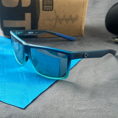 Blue and teal gradient frame sport sunglasses with polarized lenses resting on a blue cloth.