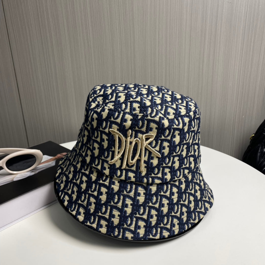 Close-up of a premium navy and beige monogram patterned bucket hat with central gold embroidery.