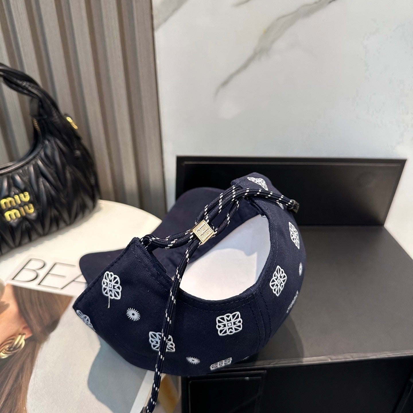Navy blue baseball cap with white embroidered paisley patterns and an adjustable back strap.