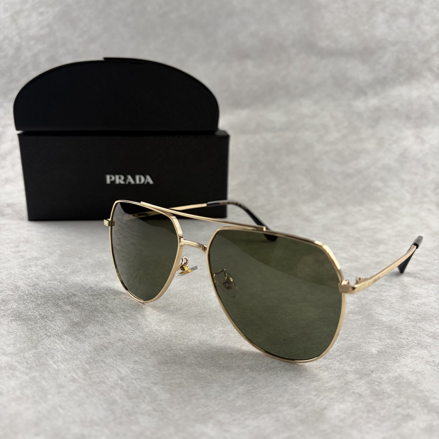 Classic gold-tone metal aviator sunglasses with tinted lenses, resting next to a protective case.