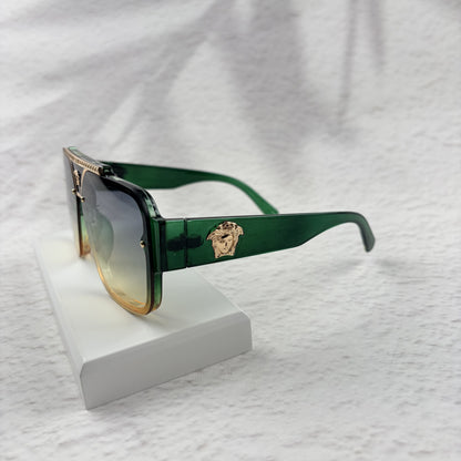 Oversized geometric sunglasses with green-to-yellow gradient lenses and gold metallic frame details.