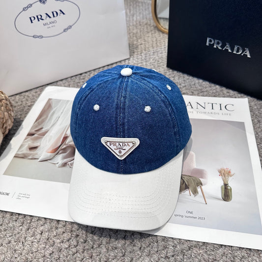 A stylish blue denim baseball cap with a white brim and a triangular metal-look logo patch.