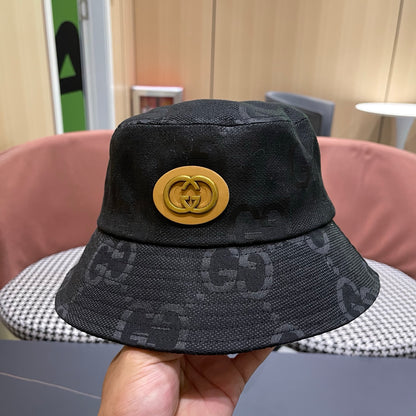 A black textured bucket hat with a circular gold emblem, featuring a monogrammed fabric design.
