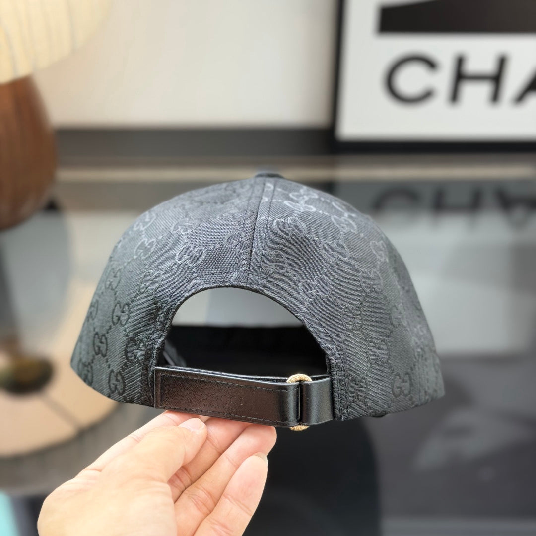 Close-up of a premium black baseball cap with a red and green center stripe and monogram pattern.