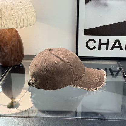 Distressed brown cotton baseball cap with frayed brim and minimalist metal circular side detail.