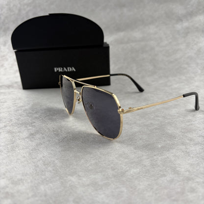 A pair of gold metal aviator sunglasses with dark lenses resting on a light grey textured background